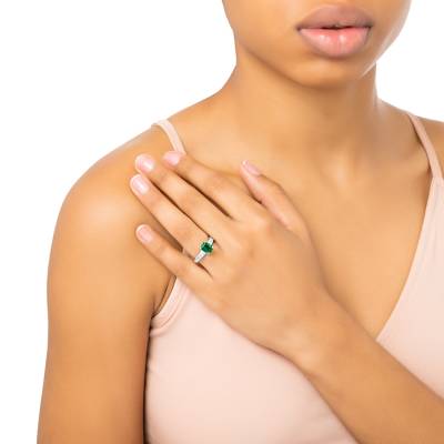Anillo compromiso de esmeralda y diamantes en mano de modelo