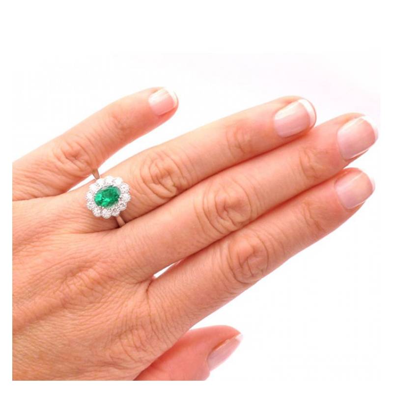 Anillo de oro rosa con esmeralda rodeada de brillantes en mano de modelo