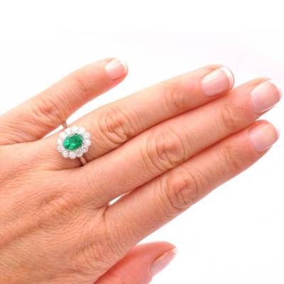 Anillo de oro rosa con esmeralda rodeada de brillantes en mano de modelo