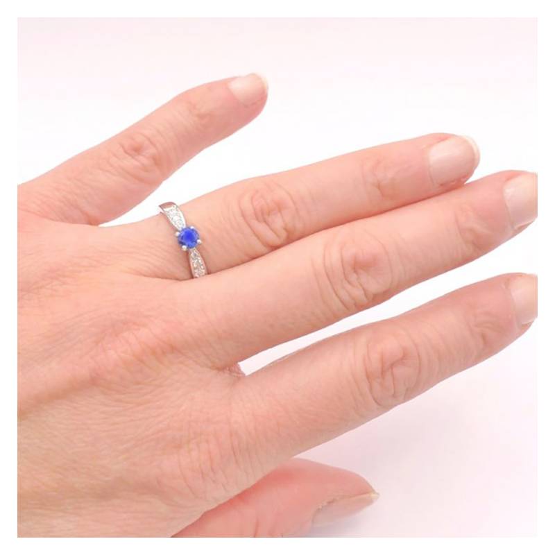 anillo de oro blanco con zafiro oval con diamantes en mano de modelo