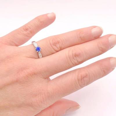 anillo de oro blanco con zafiro oval con diamantes en mano de modelo