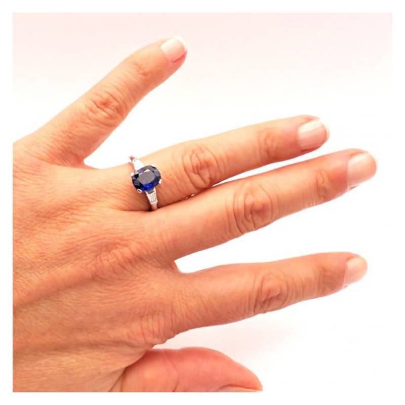 Anillo oro blanco con diamantes y zafiro de color azul en mano de modelo