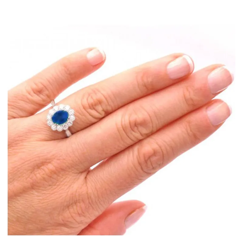 mano con Anillo clásico en oro de 18K con zafiro de 1.83 quilates y orla de diamantes F/G VS
