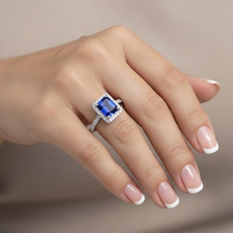 Anillo con zafiro clásico azul Royal en oro blanco y diamantes en orla rodeando la gema central, foto en mano